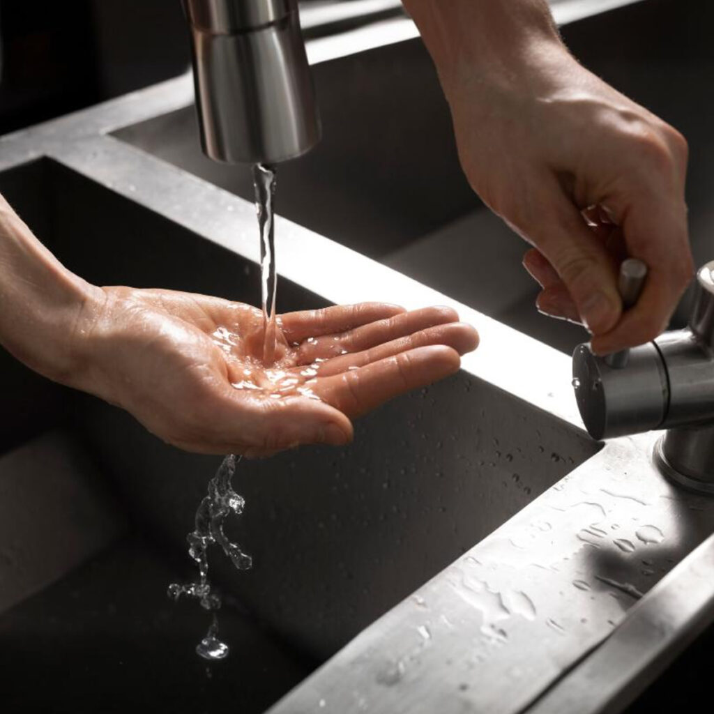 a person washing their hands under a faucet